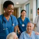 Several international nurses in blue and white uniforms caring for patients in a modern hospital corridor in Germany – symbolizing diversity and teamwork in healthcare.