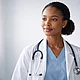 Female healthcare professional wearing scrubs and a stethoscope, standing confidently in a clinical environment